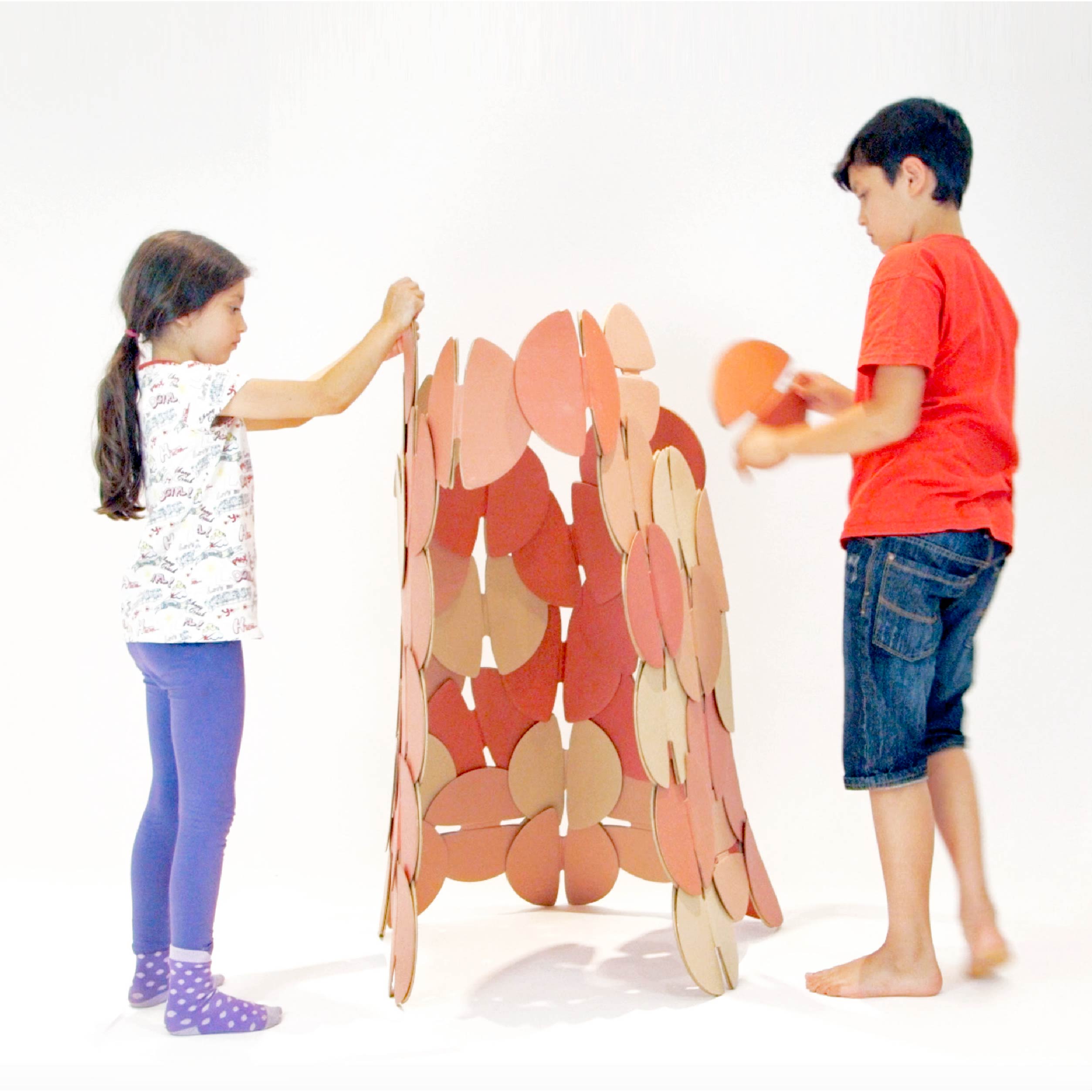Two children building a den made out of prototype noook play® discs.