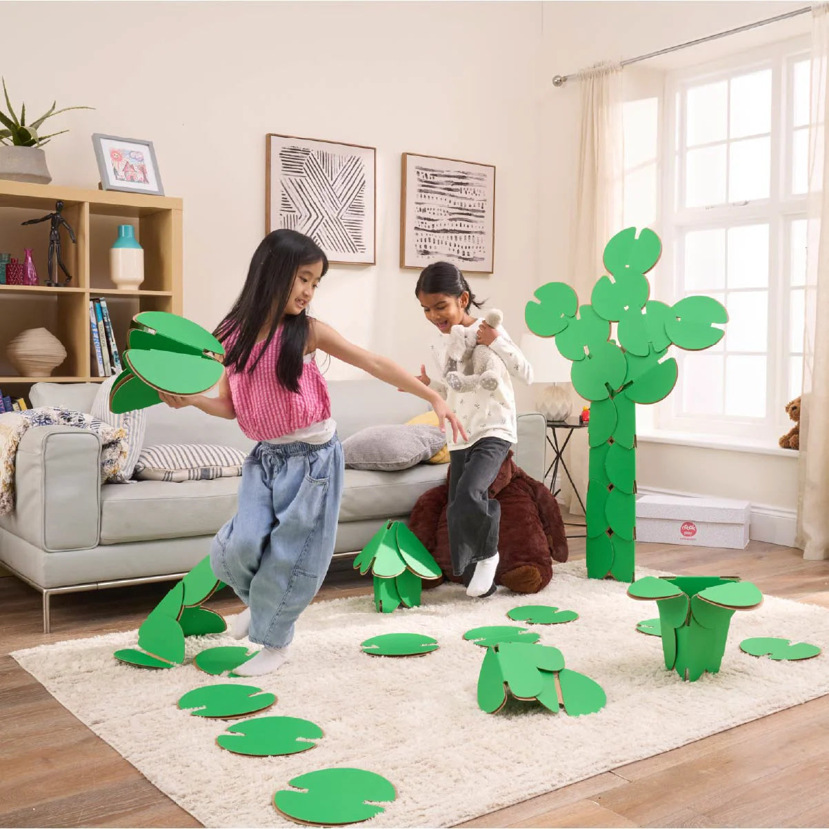 Two girls are playing in a living room, running around a magical scene made out of a noook play® building kit. The girls are jumping between trees and Lilly pads made of noook play® building discs and the girls are holding butterflies also made of noook play® building discs.
This Magic Garden took 49 noook play® discs to build.