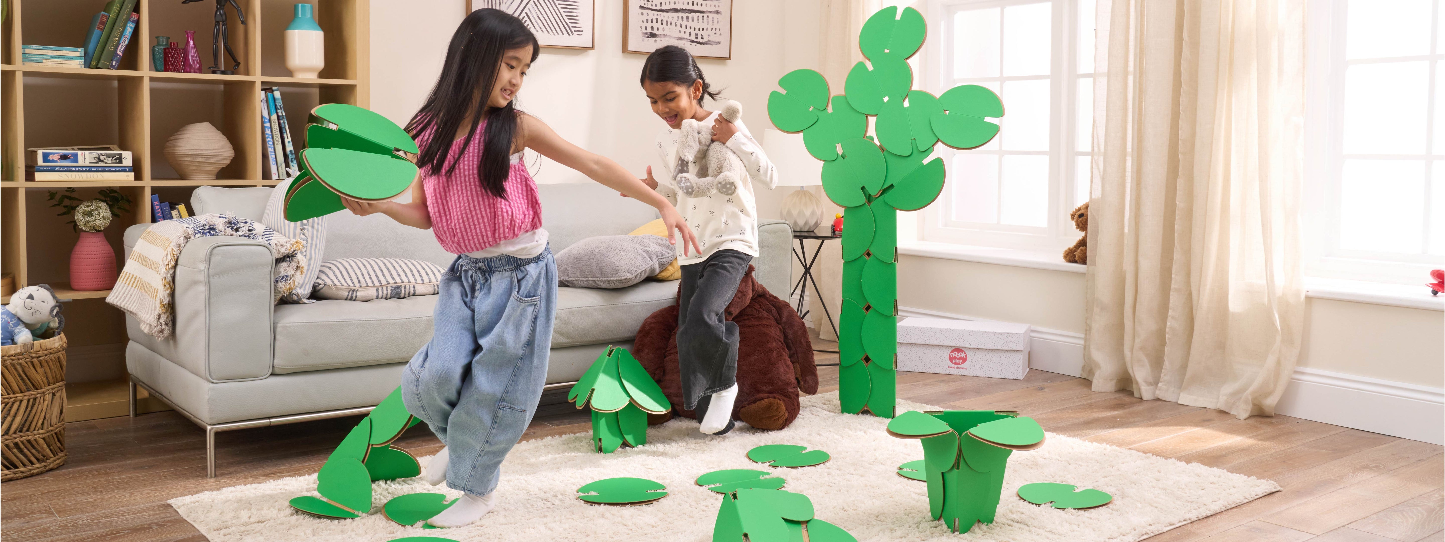 Two girls are playing in a living room, running around a magical scene made out of a noook play® building kit. The girls are jumping between trees and Lilly pads made of noook play® building discs and the girls are holding butterflies also made of noook play® building discs.
This Magic Garden took 49 noook play® discs to build.