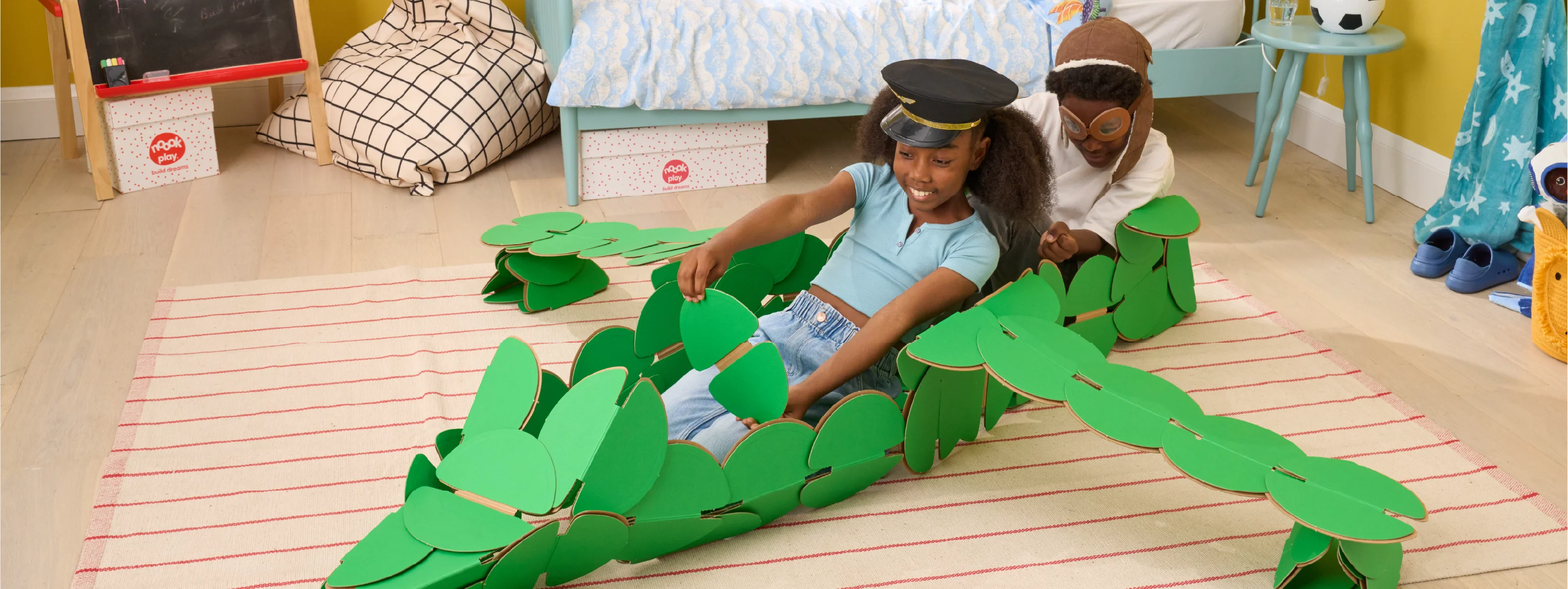 A boy and a girl pretending to be flying a fighter jet plane made out of a noook play® building kit.