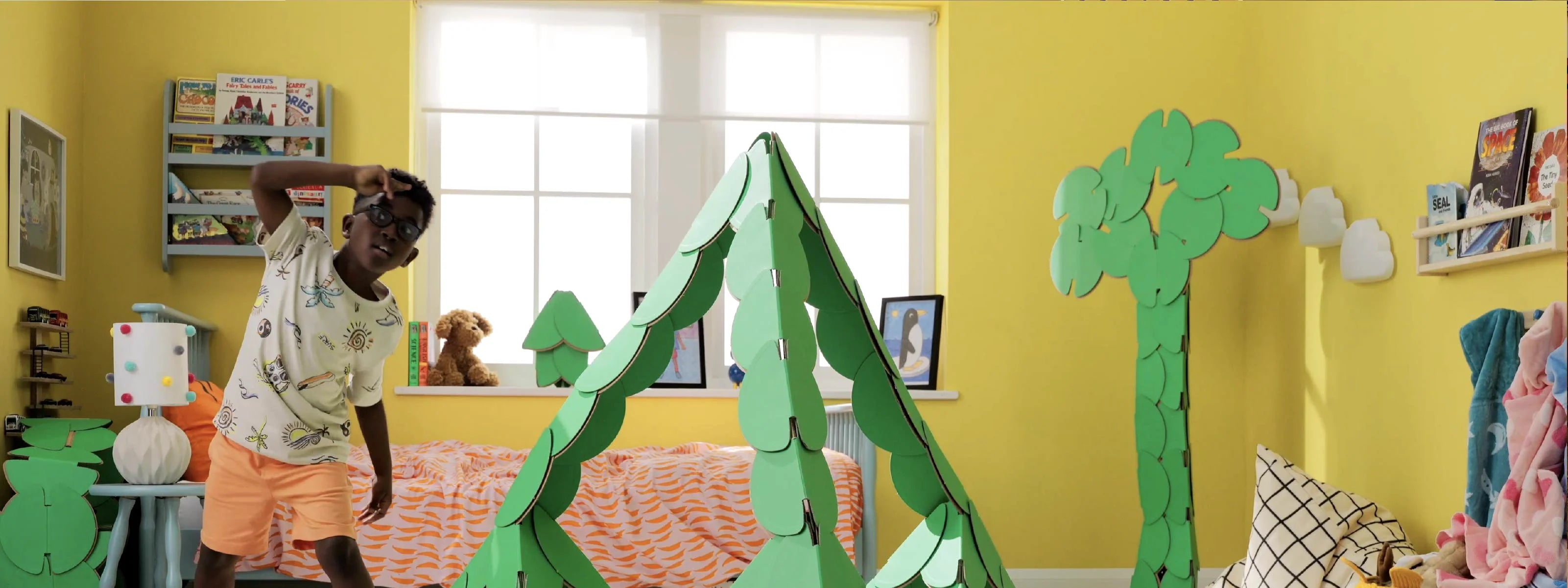Smiling child waves from inside a noook play® build, showing joy and confidence through creative play