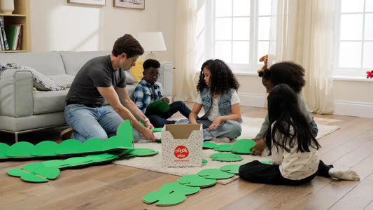 A dad building a life-sized structure with four children using green noook play discs on a living room floor