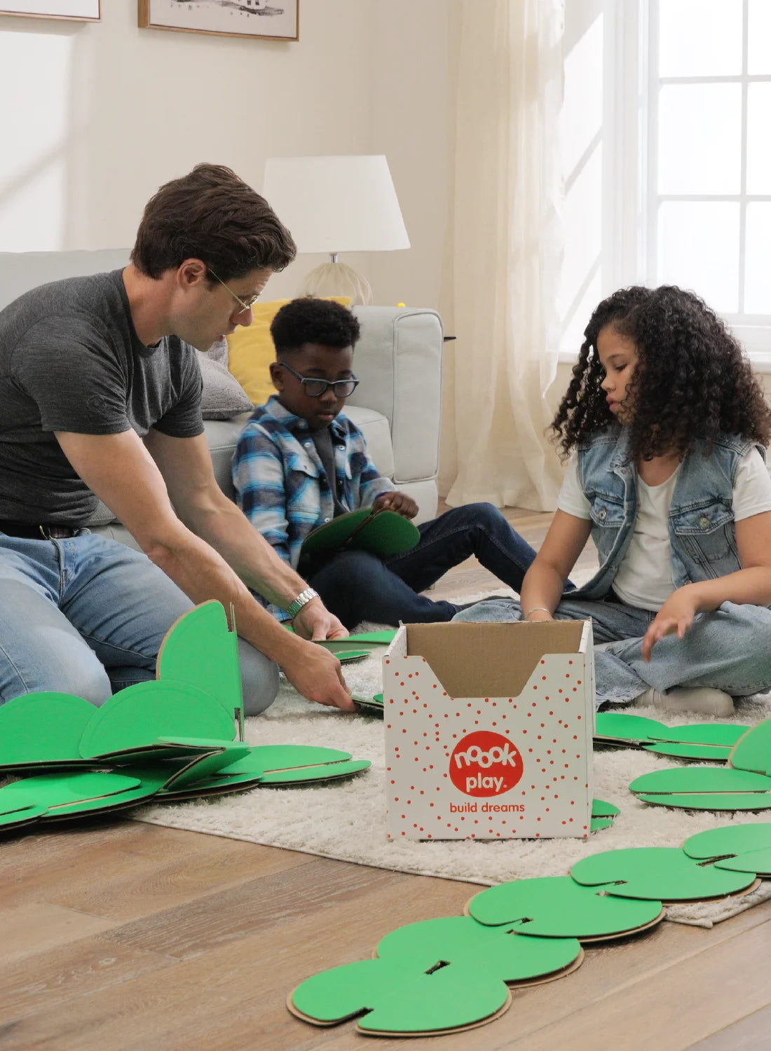 Child building with noook play® alongside an adult, learning through guided, creative play