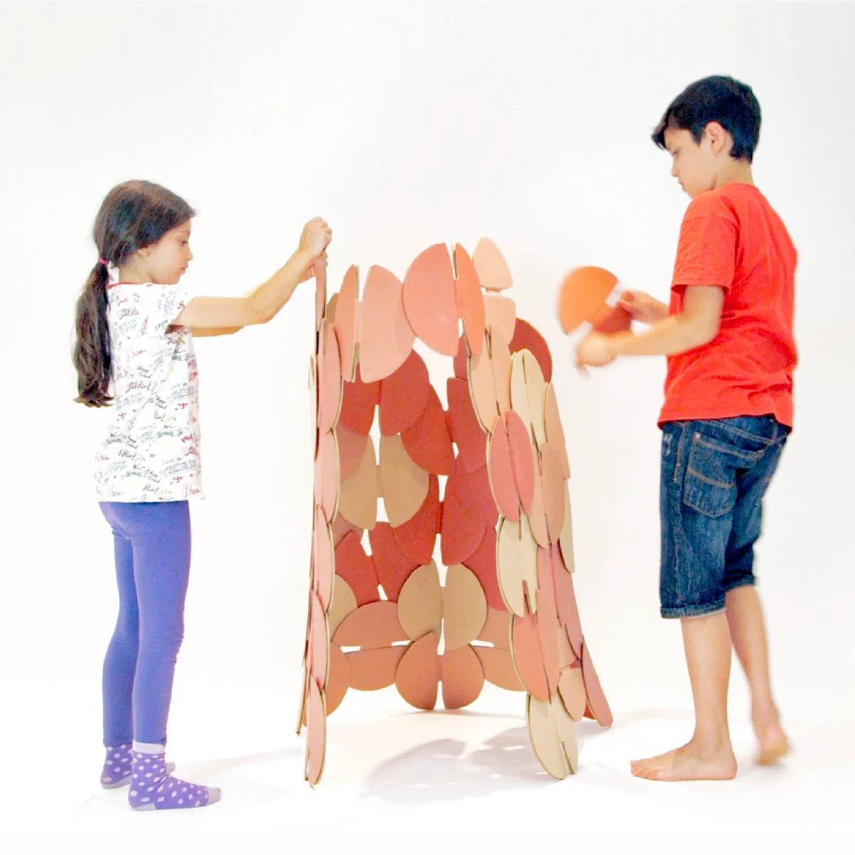 Two children building a den made out of prototype noook play® discs.