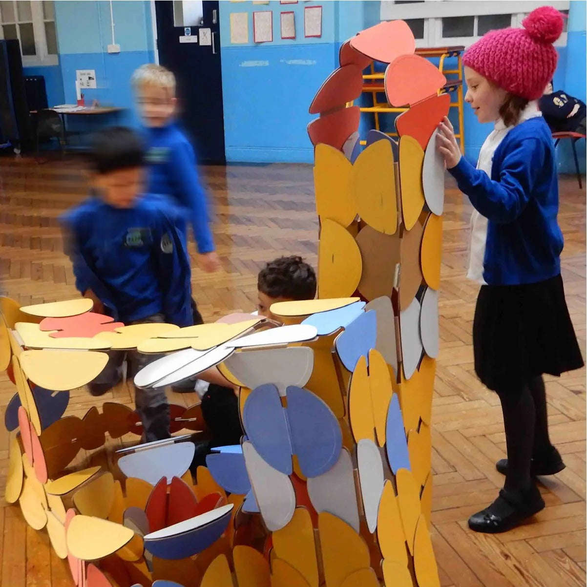 A group of school children building with noook play® discs, exploring creativity through hands-on architectural play