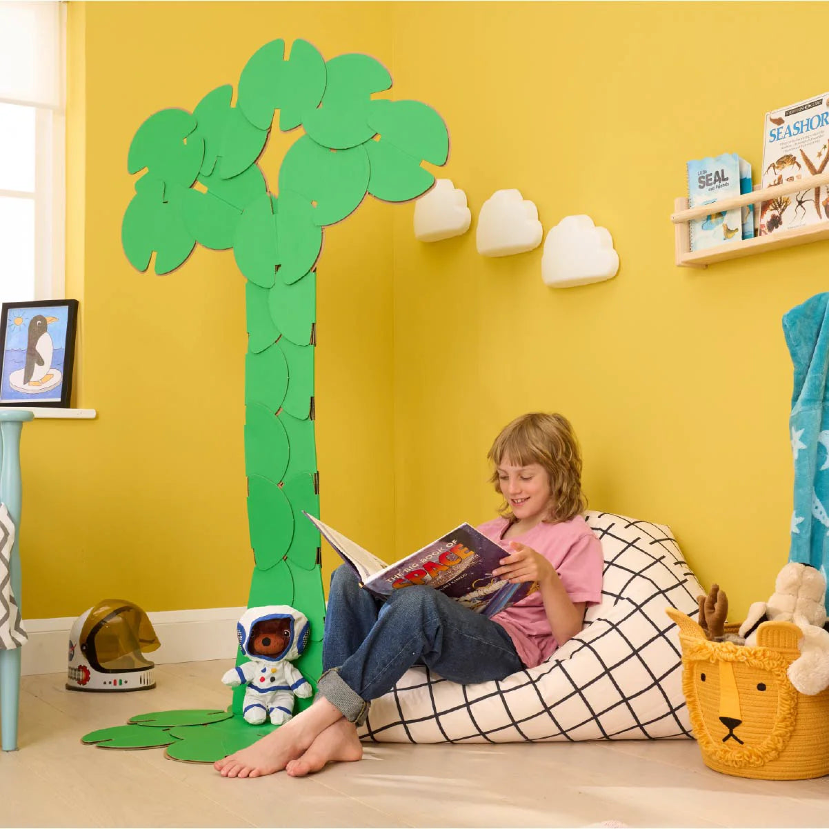 A boy reading a book in his bedroom, under a decoration made of noook play® building toys in the shape of the tree of life.
This Tree of Life took 36 noook play® discs to build.