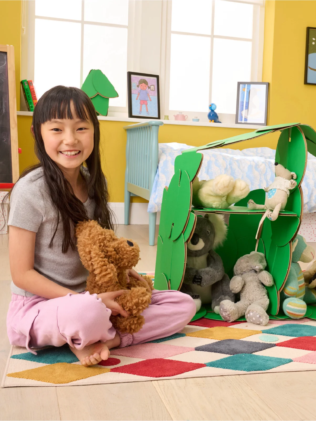 A girl plays in her bedroom with a dolls' house made out of a noook play® building kit.