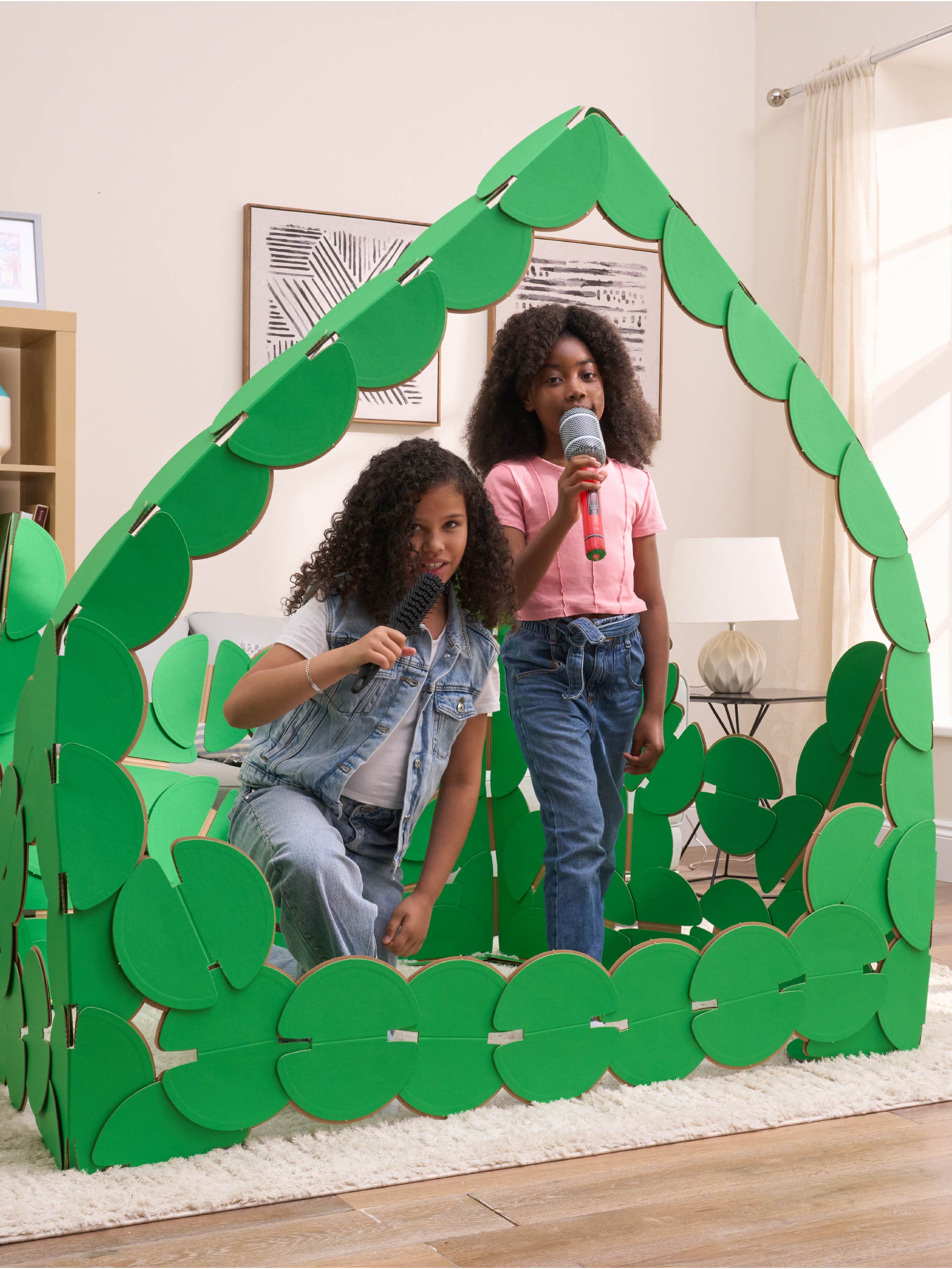 Two girls are playing in a sitting room, pretending to be pop singers on a concert stage made out of noook play® building kits. The girls are singing into microphones.
This Pop Stage took 85 noook play® discs to build.