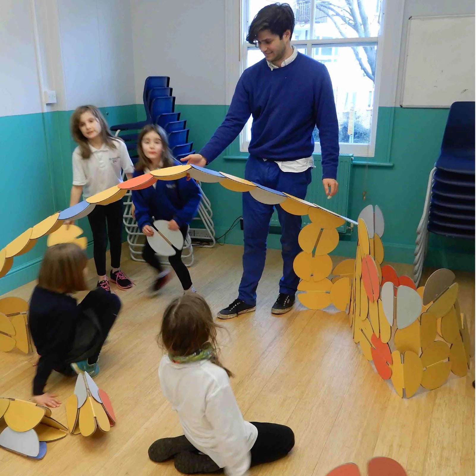 A group of school children building with noook play® discs, exploring creativity through hands-on architectural play