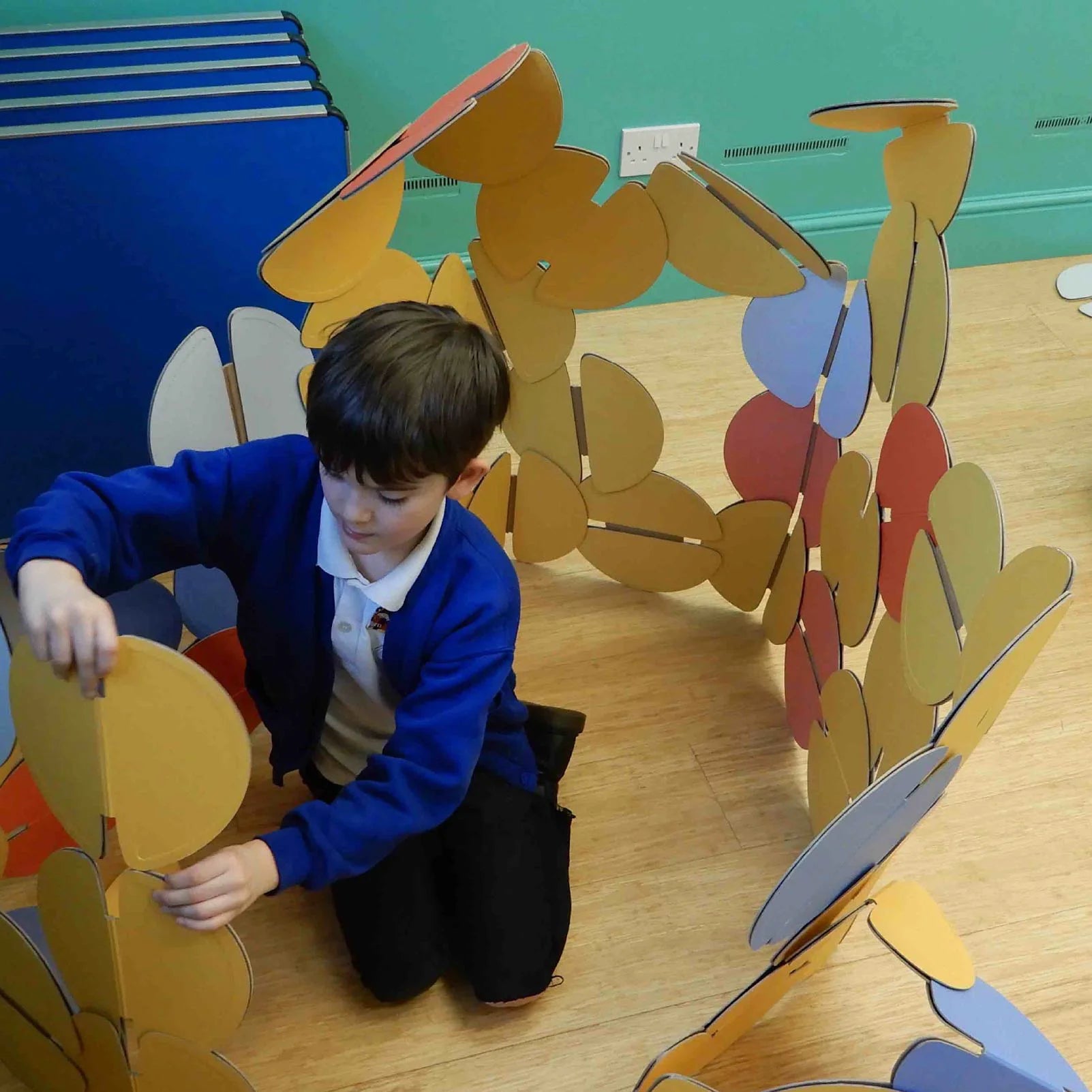 A school child building with noook play® discs, exploring creativity through hands-on architectural play