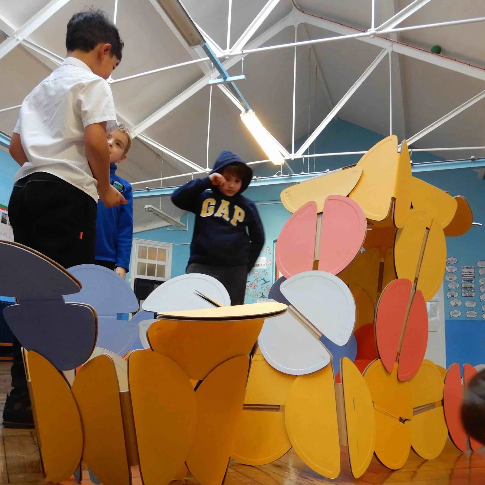 A group of school children building with noook play® discs, exploring creativity through hands-on architectural play