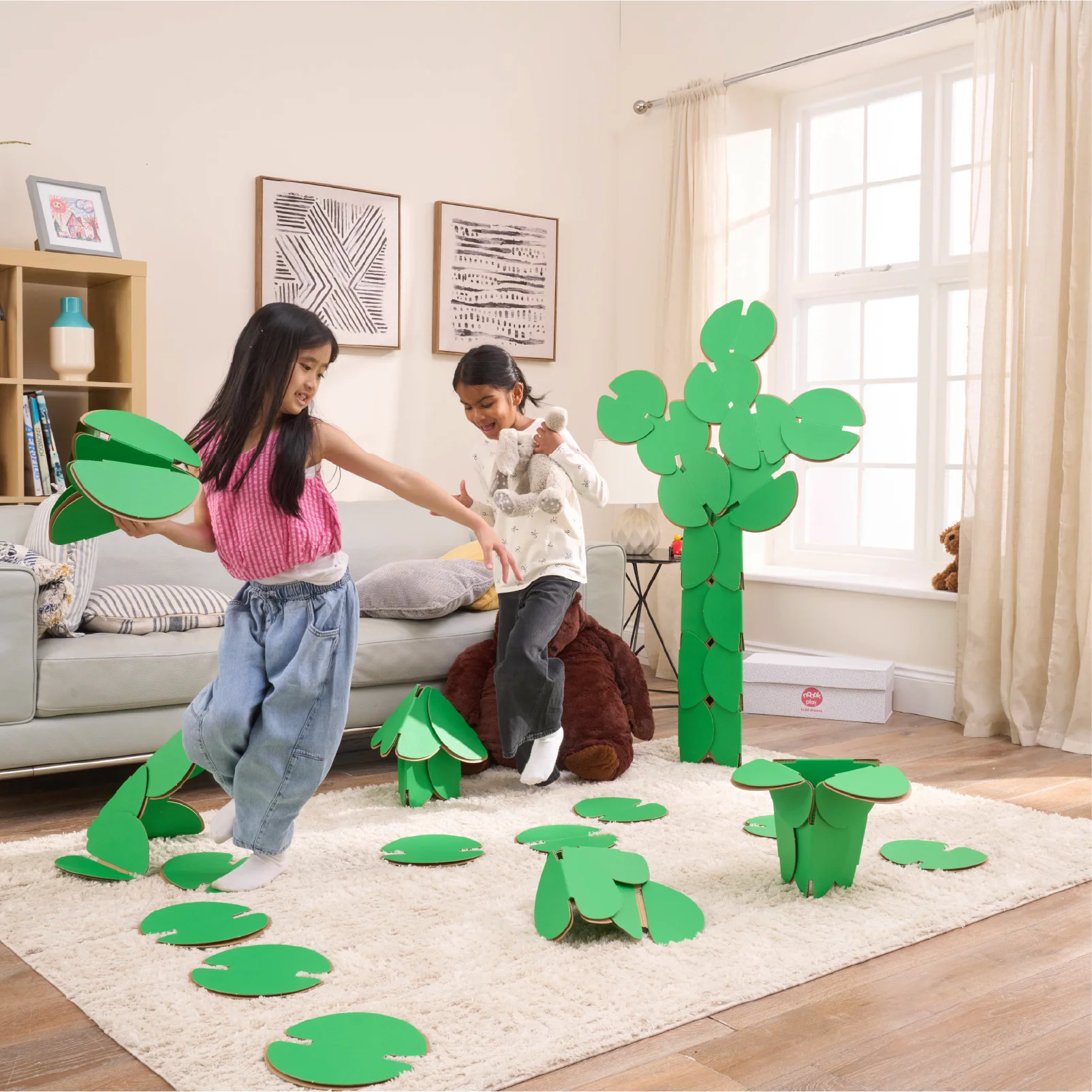 Two girls are playing in a living room, running around a magical scene made out of a noook play® building kit. The girls are jumping between trees and Lilly pads made of noook play® building discs and the girls are holding butterflies also made of noook play® building discs.
This Magic Garden took 49 noook play® discs to build.