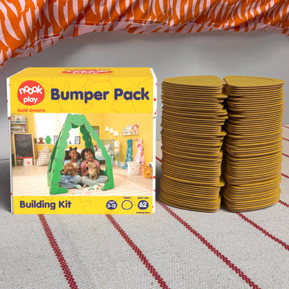 The noook play® Bumper Pack, 62 Pieces, in yellow, shown at the foot of a child bed, on a stripy rug