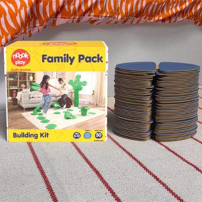The noook play® Family Pack, 50 Pieces, in blue, shown at the foot of a child bed, on a stripy rug