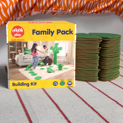 The noook play® Family Pack, 50 Pieces, in green, shown at the foot of a child bed, on a stripy rug