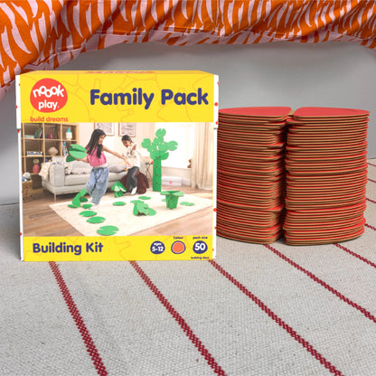 The noook play® Family Pack, 50 Pieces, in red, shown at the foot of a child bed, on a stripy rug
