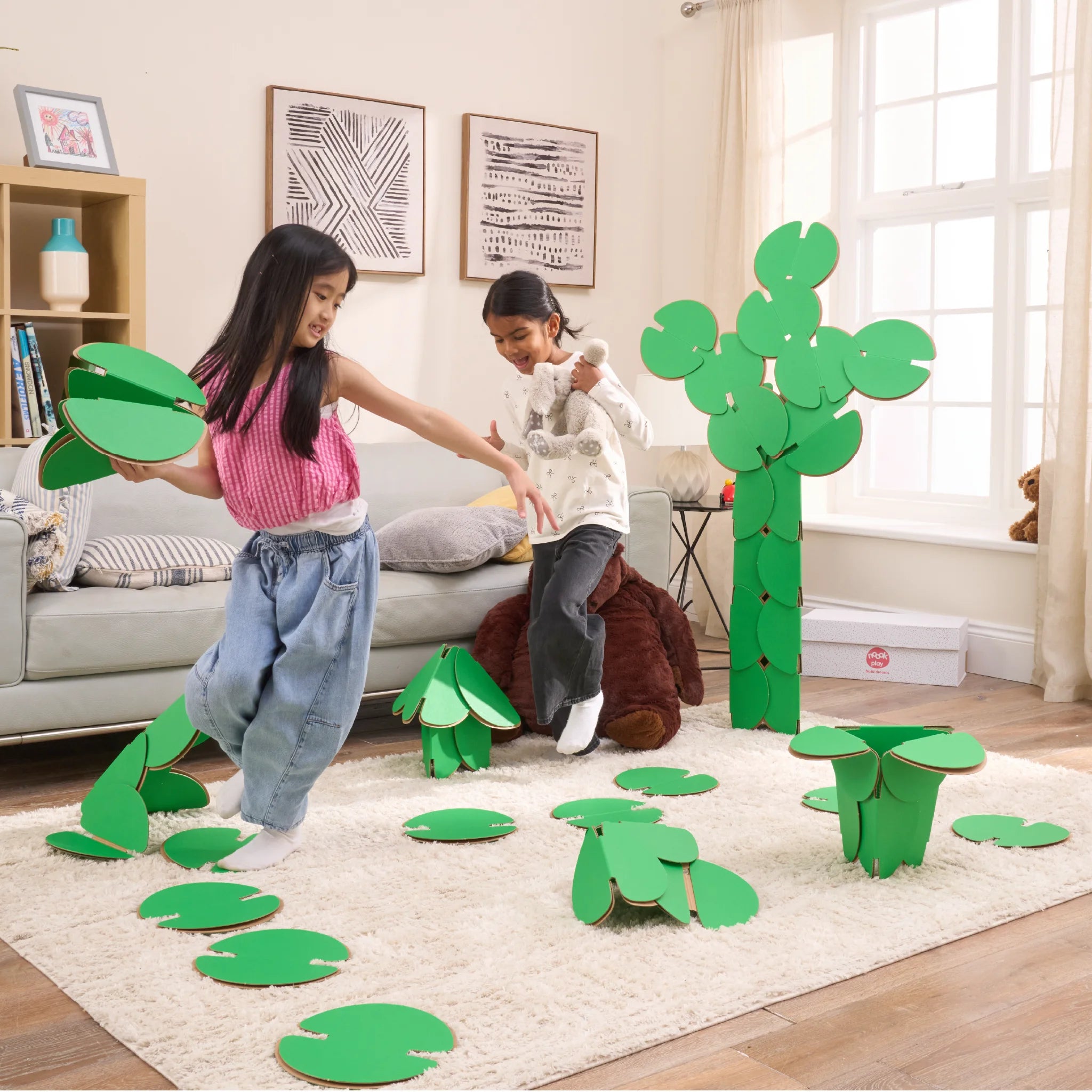 Two girls are playing in a living room, running around a magical scene made out of a noook play® building kit. The girls are jumping between trees and Lilly pads made of noook play® building discs and the girls are holding butterflies also made of noook play® building discs.
This Magic Garden took 49 noook play® discs to build.