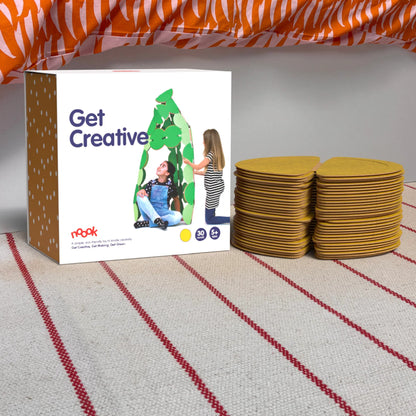 The noook play® Starter Pack, 30 Pieces, in yellow, shown at the foot of a child bed, on a stripy rug