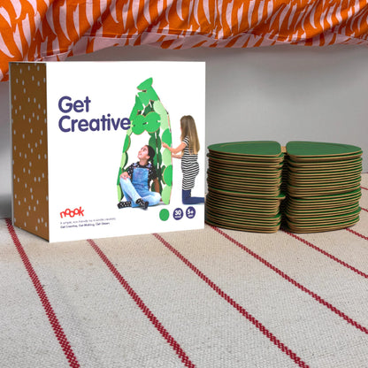 The noook play® Starter Pack, 30 Pieces, in green, shown at the foot of a child bed, on a stripy rug