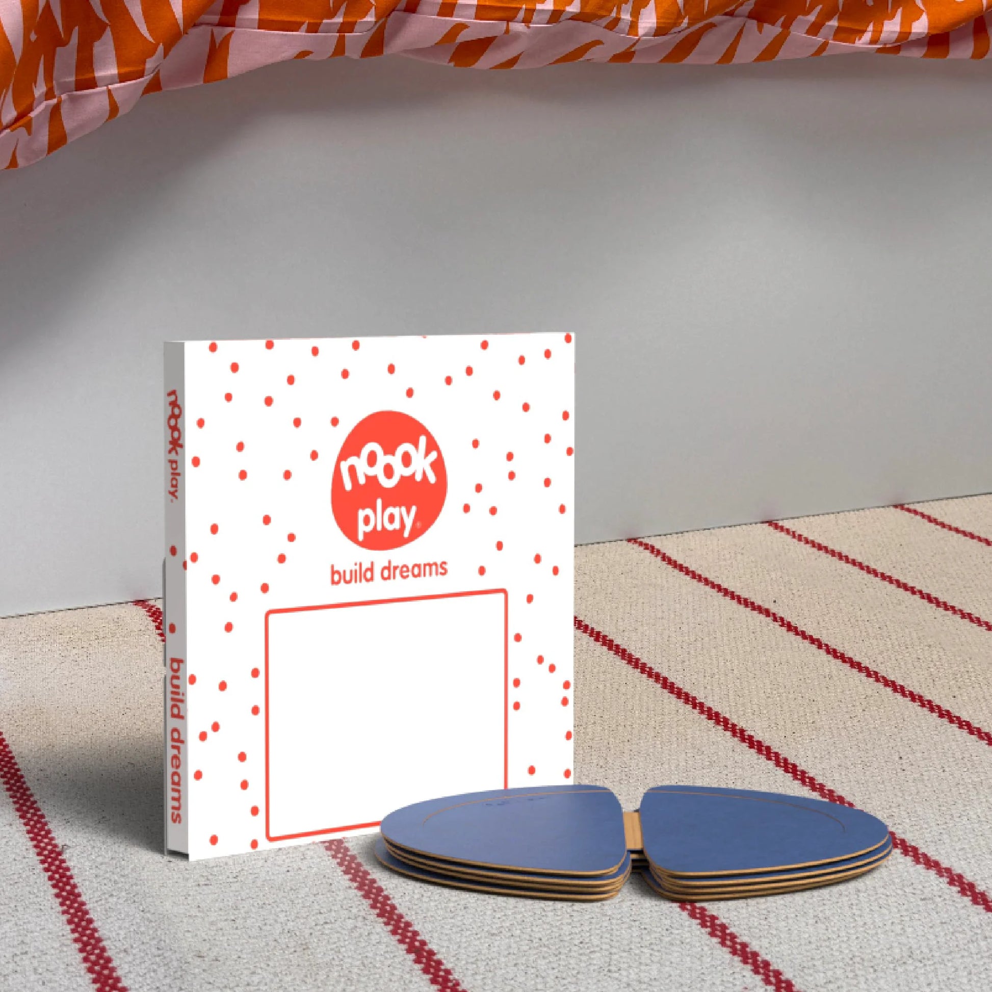 The noook play® Top-Up Pack, 12 Pieces, in blue, shown at the foot of a child bed, on a stripy rug