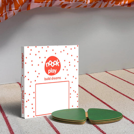 The noook play® Top-Up Pack, 12 Pieces, in green, shown at the foot of a child bed, on a stripy rug