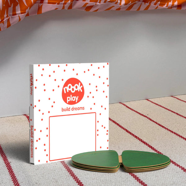 The noook play® Top-Up Pack, 12 Pieces, in green, shown at the foot of a child bed, on a stripy rug