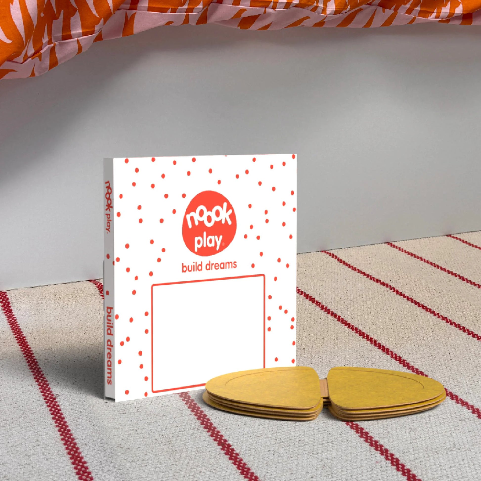 The noook play® Top-Up Pack, 12 Pieces, in yellow, shown at the foot of a child bed, on a stripy rug