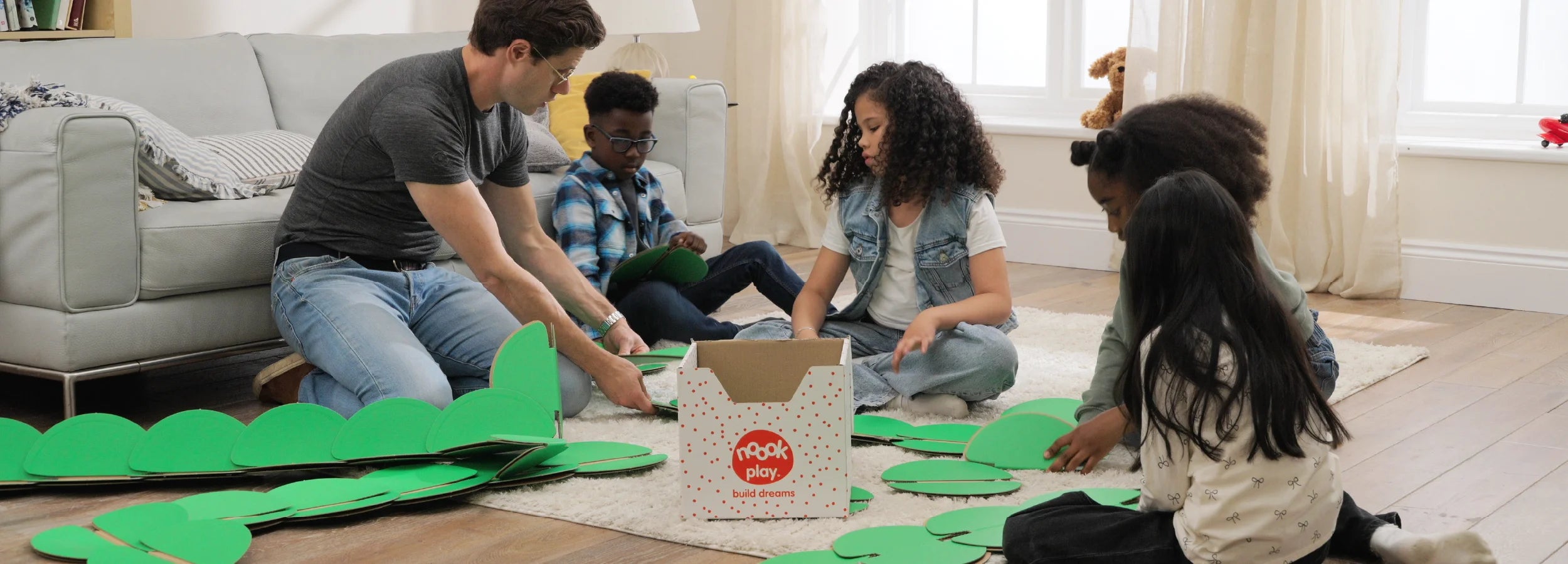 Child building with noook play® alongside an adult, learning through guided, creative play