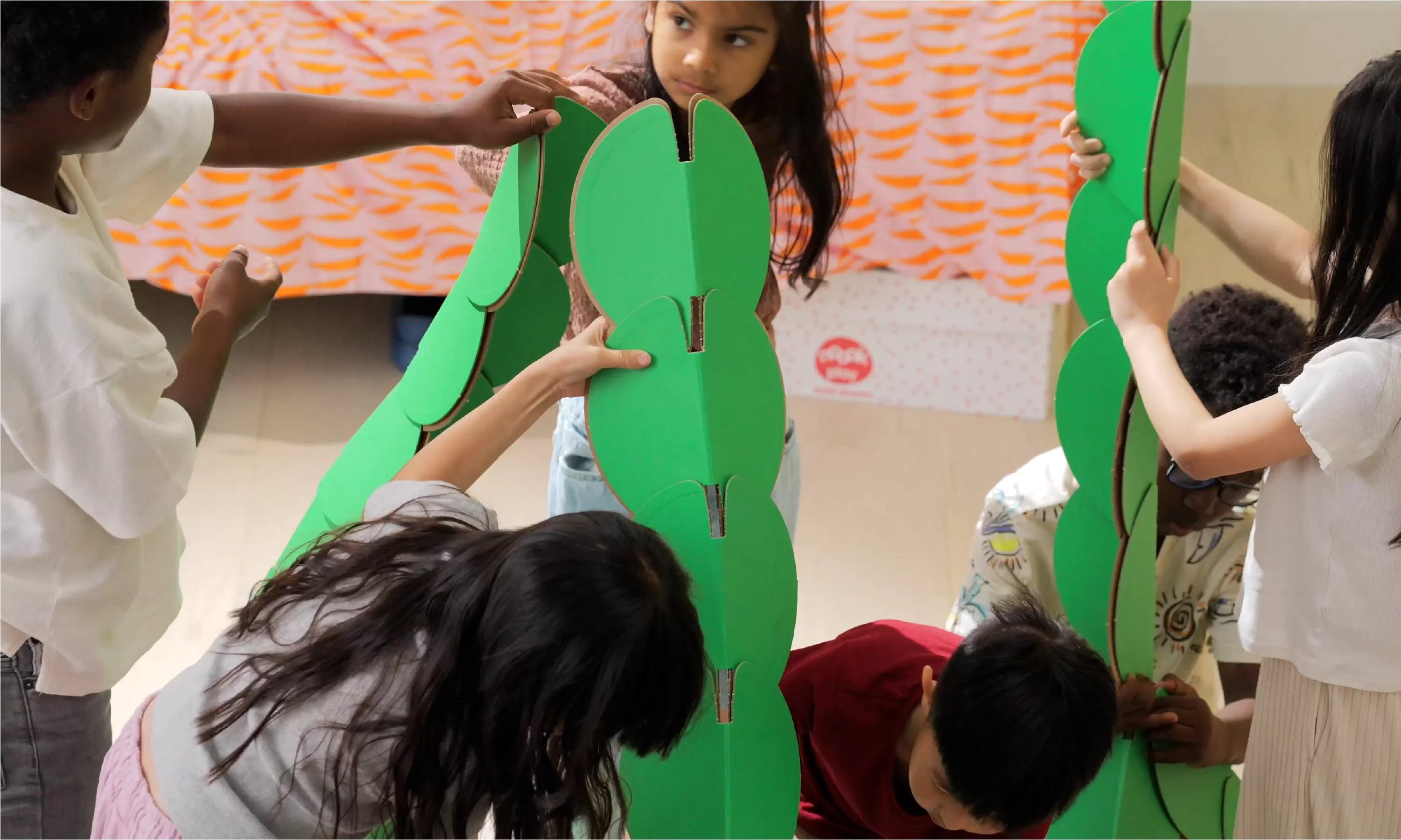 Children build pyramid structures with noook play® discs, exploring geometry and teamwork through play