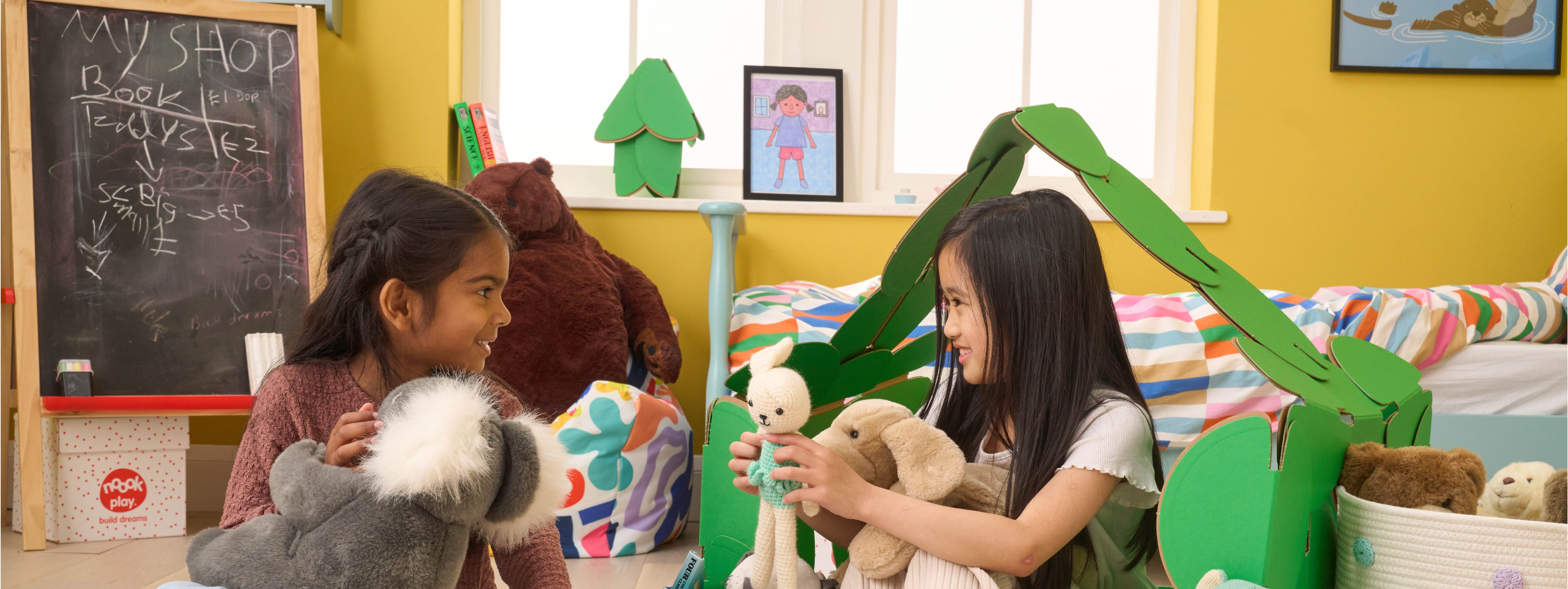 Two girls playing shop keepers, selling teddies from a shop made out of a noook play® building kit.