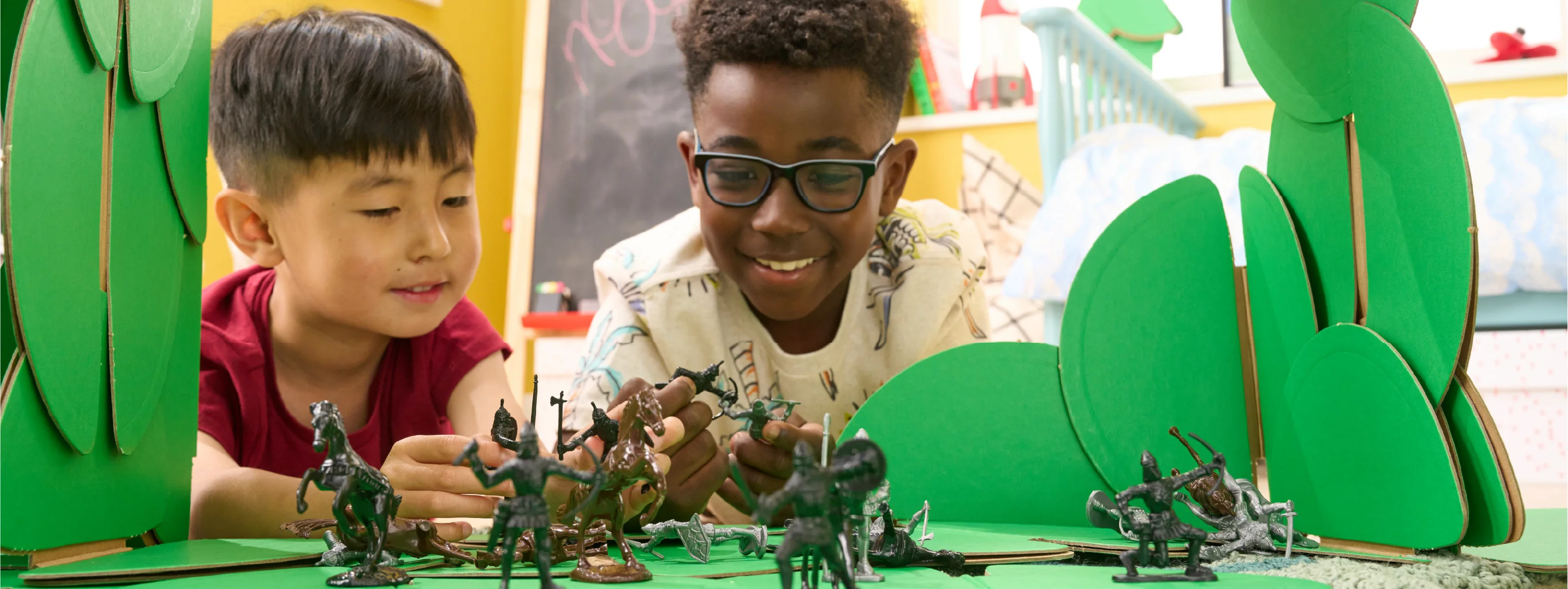 Two boys are playing with knights and horses in a scene made out of a noook play® building kit.