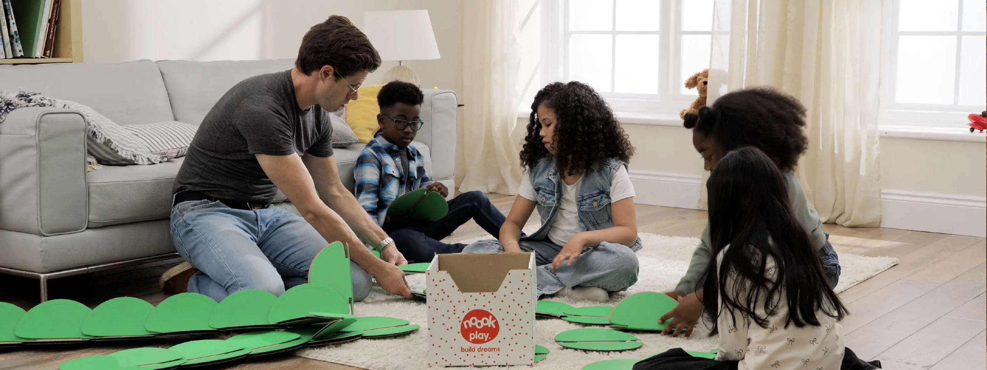 Child building with noook play® alongside an adult, learning through guided, creative play