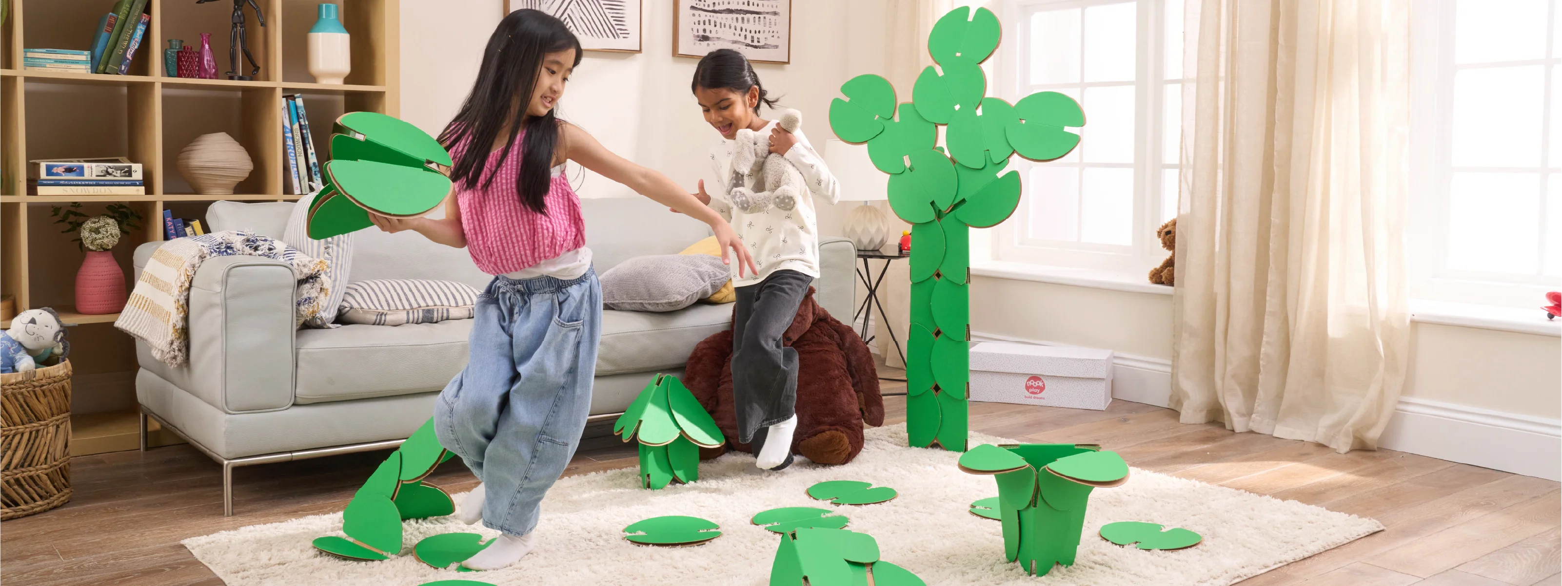 Two girls are playing in a living room, running around a magical scene made out of a noook play® building kit. The girls are jumping between trees and Lilly pads made of noook play® building discs and the girls are holding butterflies also made of noook play® building discs.
This Magic Garden took 49 noook play® discs to build.